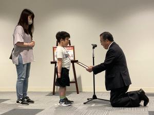 10万人目の認定証を読み上げる様子